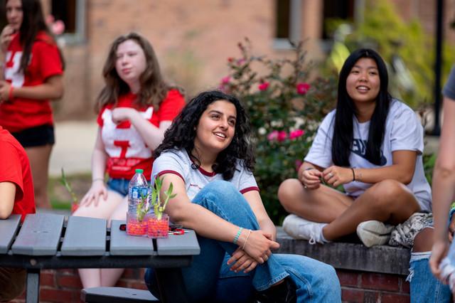 Student smiling at other student on a bench